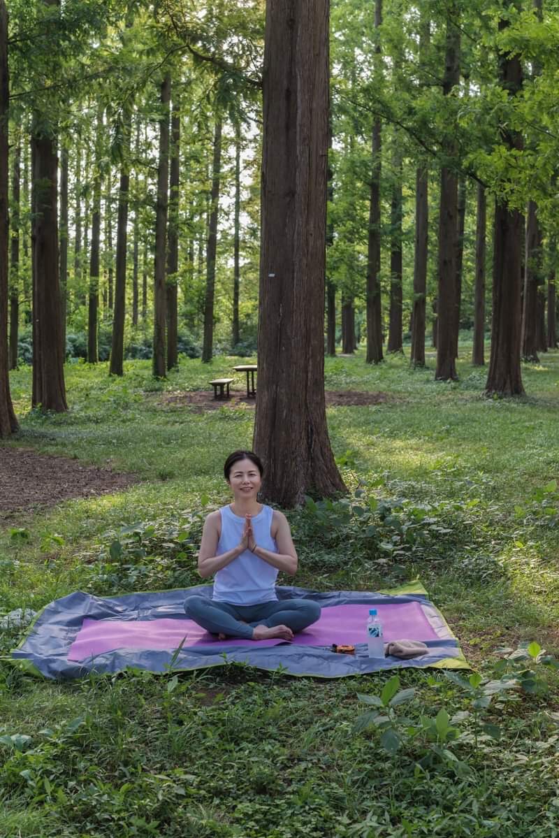 森の中で座って合掌する講師 miyabi